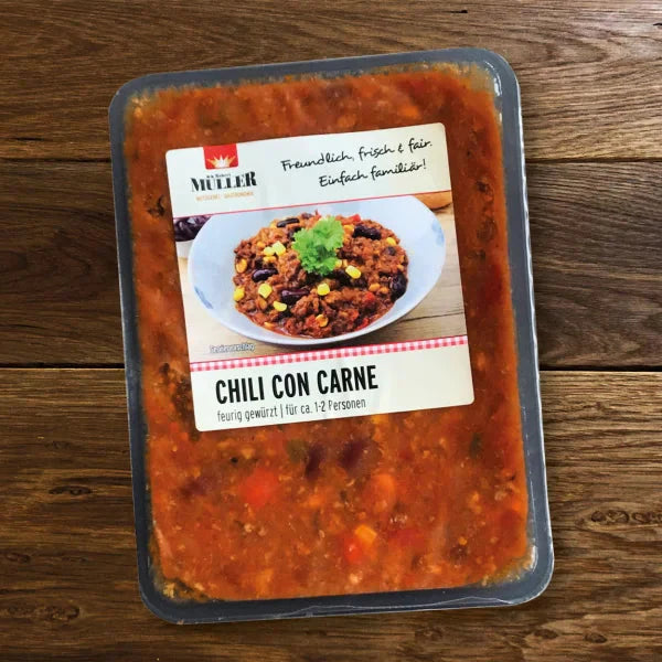Müller Chili con Carne fertig verpackt, feurig gewürzt für 1-2 Personen, auf einem Holztisch