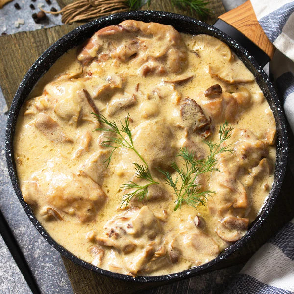 Lendentopf in Champignon-Rahmsauce, serviert in einer schwarzen Pfanne mit frischen Kräutern