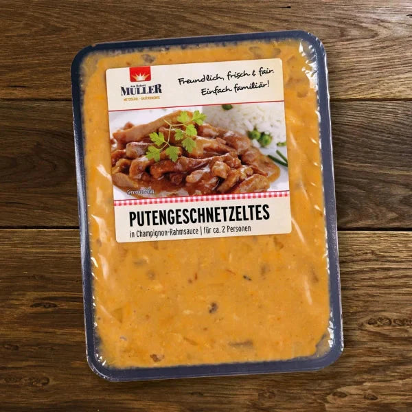 Müller Putengeschnetzeltes in Champignon-Rahmsauce, fertig verpackt für ca. 2 Personen, auf einem Holztisch