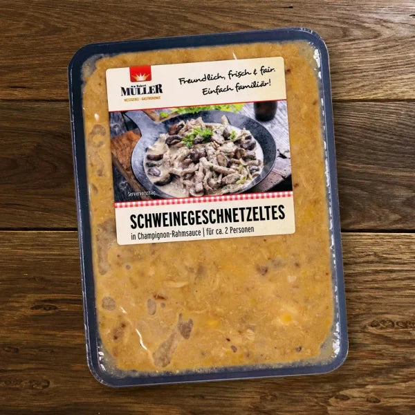Müller Schweinegeschnetzeltes in Champignon-Rahmsauce, fertig verpackt für ca. 2 Personen, auf einem Holztisch