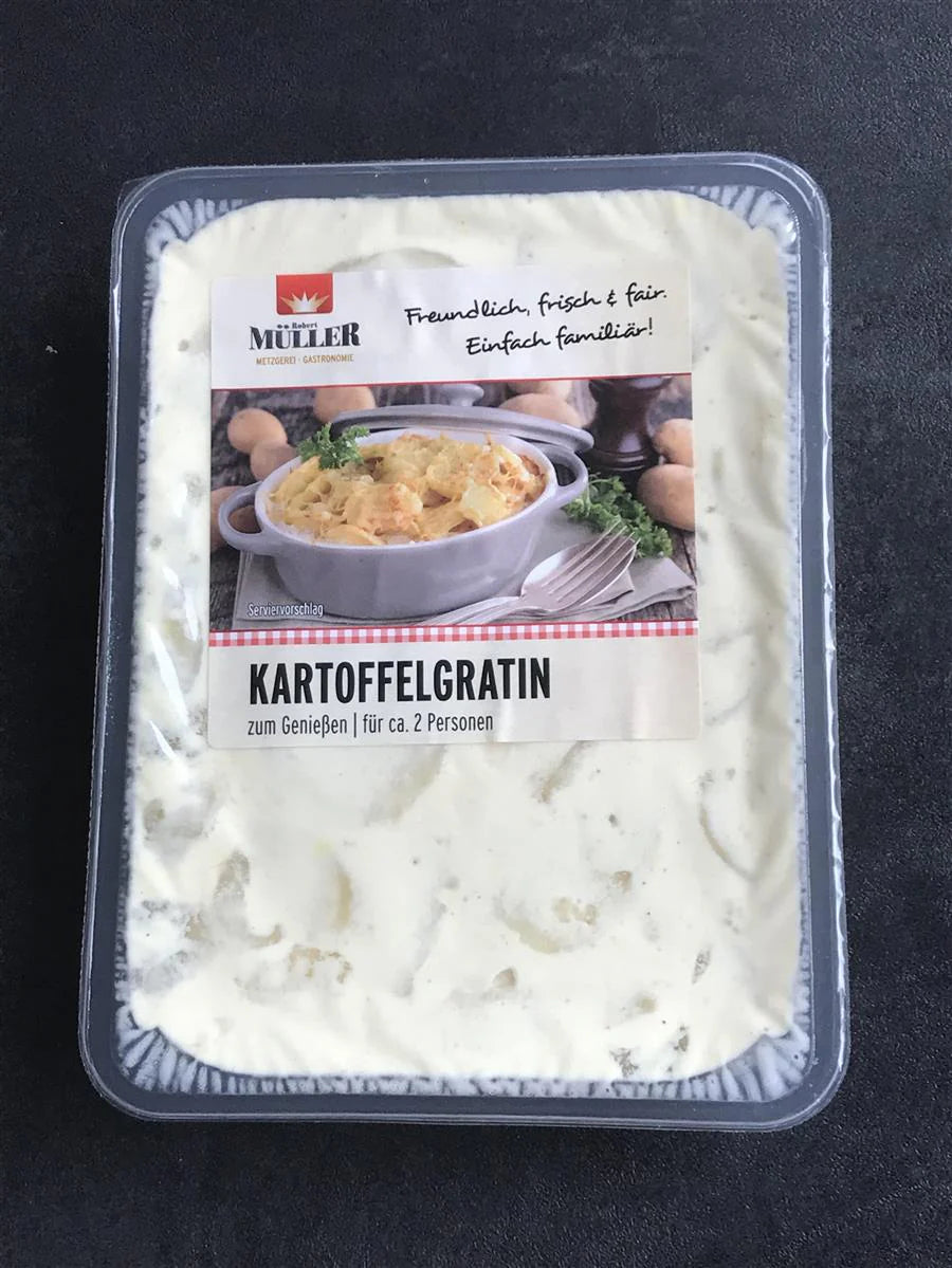Müller Kartoffelgratin, fertig verpackt für ca. 2 Personen, auf einem dunklen Tisch