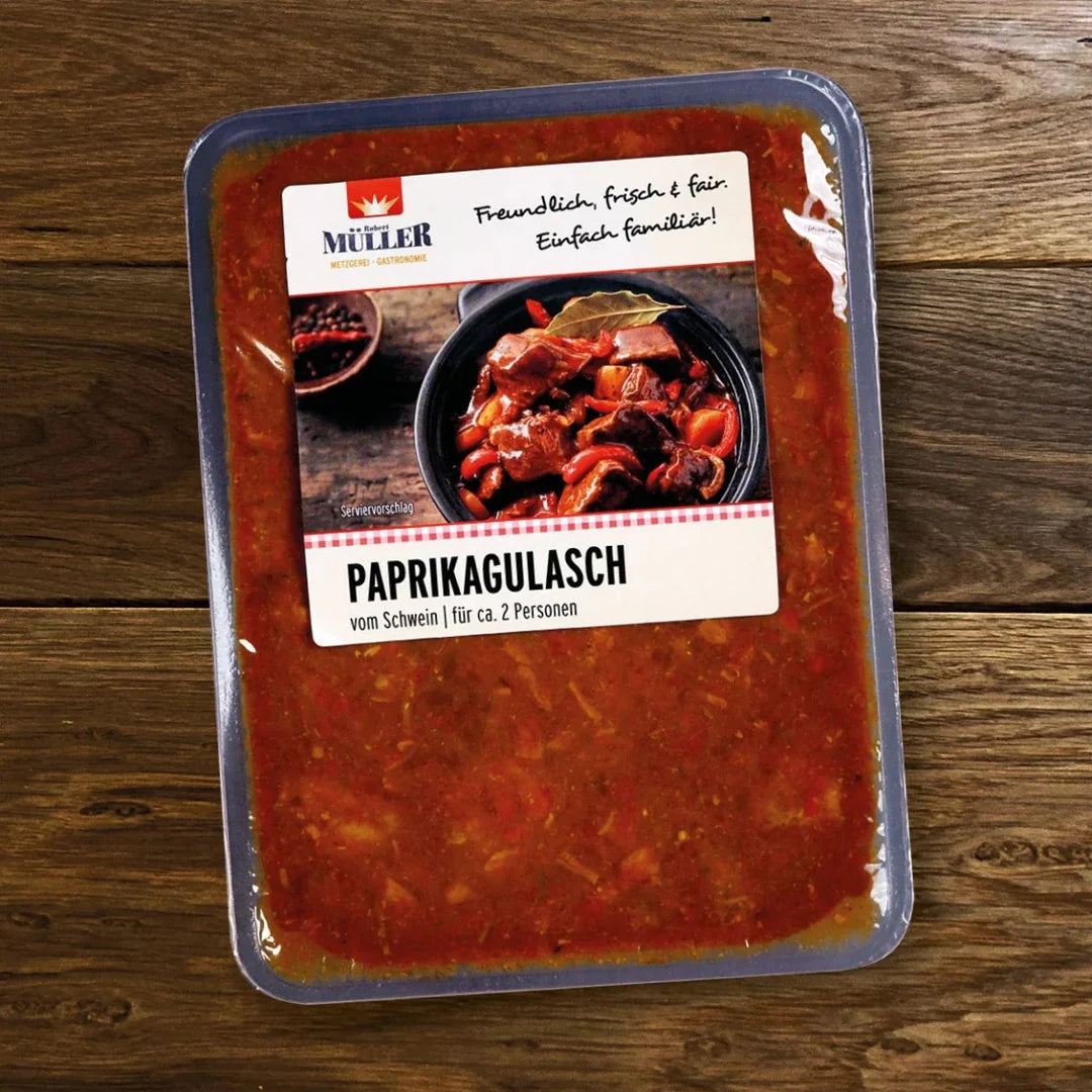 Müller Paprikagulasch vom Schwein, fertig verpackt für ca. 2 Personen, auf einem Holztisch