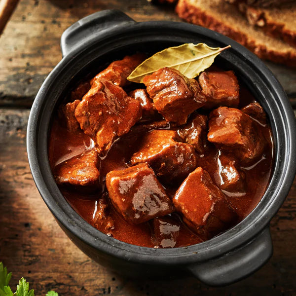 Rindersaftgulasch in einem schwarzen Topf, serviert mit zarten Fleischstücken in einer herzhaften Soße