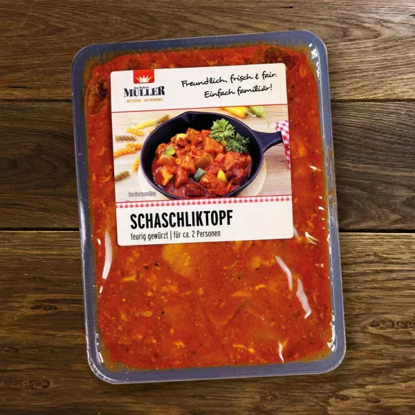 Müller Schaschliktopf, fertig verpackt in einer würzigen Soße für ca. 2 Personen, auf einem Holztisch